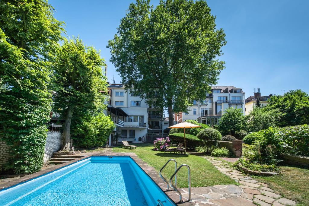 Schöner Garten mit Swimmingpool und üppiger Vegetation, umgeben von Bäumen und Sträuchern, ideal für entspannende Sommertage in einer ruhigen Wohngegend.