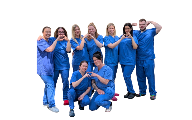 Das Pflegeteam der LipoClinic Dr. Heck in blauer Arbeitskleidung, neun Personen formen mit den Händen Herzen